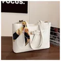 Close-up of white crocodile pattern tote bag with decorative silk scarf on handle - White