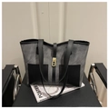 Bolso tote bicolor en gris y negro con elegante cierre giratorio dorado sobre una silla - Negro