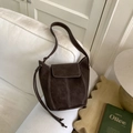 Détail du sac seau marron foncé avec surpiqûres blanches sur un fond de canapé blanc - Sans Pendentif / Café