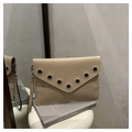 Detail der beigen Umschlag-Clutch mit Metallösen auf einer matten Leder-Oberfläche - Khaki
