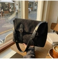 Detail of black matte messenger bag with golden buckle and leather strap in a cafe setting - Black