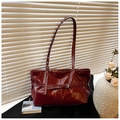 Detail view of burgundy patent leather handbag with adjustable buckle strap and high gloss finish - Red