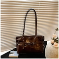 Detail of a dark brown glossy tote bag with adjustable shoulder strap and buckle - Brown