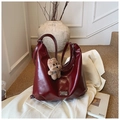 Macro detail of glossy dark red leather tote bag featuring a cute brown plush bear charm - Burgundy With Pendant
