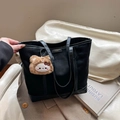 Black matte tote bag with leather handles and a brown plush animal pendant charm - Black With Pendant