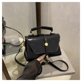 Detalle del bolso pequeño cuadrado negro brillante con hebilla dorada en un taburete - Negro