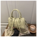 Détails des clous métalliques argentés et des longs zips à pompons sur un sac Boston crème - Jaune