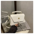 Detalle de un bolso de cuero blanco con cierre dorado circular y asa superior - Blanco