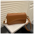 Detail view of the caramel brown crossbody bag with unique wave design and gold hardware - Brown