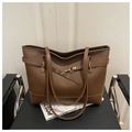 Détail d'un sac cabas marron foncé avec texture grainée et boucles métalliques décoratives - café