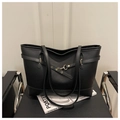 Détail d'un grand sac cabas noir en cuir grainé avec boucles métalliques sur une chaise - Noir
