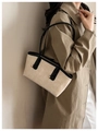 Modell mit großer beiger Shopper-Tasche aus Mattleder mit schwarzen Riemen und Goldbuckeln - Gebrochenes Weiß