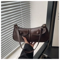 Detail of dark brown underarm bag with glossy texture and double front flap pockets - Coffee