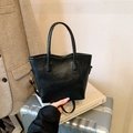 Sac seau minimaliste en cuir noir avec poignées posé sur une valise argentée - Sans Pendentif / Noir