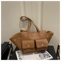 Close-up of brown pebbled leather tote bag featuring two front pockets and golden logo - Brown