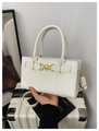 Detail van witte mat leren handtas met gouden hartsluiting op een witte koffer - Wit