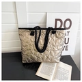 Detail of gold metallic tote bag with star quilting and black rope handles - Gold