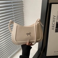 Bolso de mano beige elegante con lazo metálico y correa de hombro anudada en luz suave - Blanco