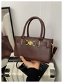 Detail of vintage brown leather handbag with gold heart buckle on a retro suitcase - Coffee