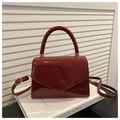 Detalle de bolso en charol burdeos con solapa en V y herrajes dorados de lujo - Rojo