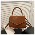 Detalle del bolso de charol marrón brillante con solapa en V y asa superior minimalista - Marrón