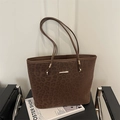 Brown leopard print tote bag in suede texture with gold metal accents on a black leather chair - Coffee