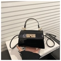 Detail view of glossy black patent leather bag with a luxury gold rotating lock - Glossy Patent Style / Black