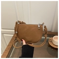 Minimalist brown crossbody bag with silver zipper and knot detail strap shown in hand - Brown