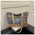 Blue denim tote bag with tan leather trim and golden buckle detail on black sofa - Blue and Khaki