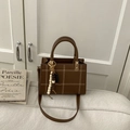 Detailed view of brown square crossbody bag with white stitching and wooden bead charm - Brown with Pendant