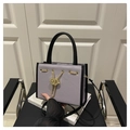 Lila Tasche mit Kieselmaserung, schwarzem Rand und goldener Kette auf dezentem Sitz - Lila