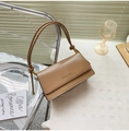 Detalle de bolso de cuero marrón con cadena dorada y elegante correa de nudo - Caqui