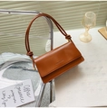 Detailed view of caramel leather baguette bag with knot strap and brand logo display - Light Brown