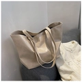 Detail view of large beige leather tote bag on a sofa with cozy white knit cardigan - Khaki