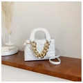 Detail of white quilted handbag with thick gold chain on a wooden shelf in a minimalist setting - White