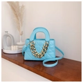 Detailed view of sky blue quilted handbag with gold chain handle on wooden shelf - Blue
