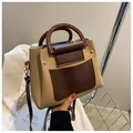 Détail d'un sac carré chic bicolore abricot et marron avec poignée arquée brillante - Kaki