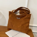 Bolso tote de pana marrón caramelo con correa ancha y etiqueta sobre madera rústica - Marrón