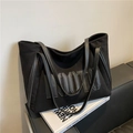 Sac cabas chic en daim noir avec lettrage MMTH brodé en 3D posé sur un canapé en cuir - Noir