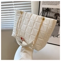 Close-up of white quilted tote bag featuring a gold chain strap and elegant faux leather texture - White