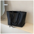 Détail d'un sac cabas en cuir tressé noir avec de longues bandoulières dans un décor épuré - Noir