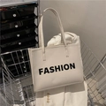 Bolso tote blanco roto con estampado de letras FASHION en un carrito de metal - Blanco