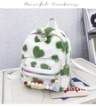 Detail of white plush backpack with green heart patterns and colorful pompoms inside PVC pocket - Green