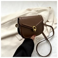 Detail of a brown leather saddle bag with a golden double-ring buckle on a beige blazer - Brown