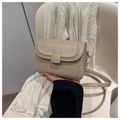 Primer plano de un bolso bandolera beige de piel sintética con solapa y hebilla - Caqui