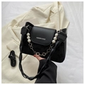 Detalle de bolso negro de cuero y ante con cadena de perlas y texto de moda grabado - Negro