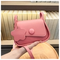 Détail d'un sac bandoulière rose en cuir texturé avec un charmant pendentif floral - Rose