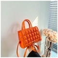 Detail of bright orange quilted PU leather handbag with sleek top handles and shoulder strap - Orange