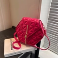 Magenta hexagon crossbody bag with quilted geometry and gold tassel on art book - Fuchsia