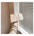 Detail of white leather underarm bag featuring a minimalist flap and gold metal accents - White